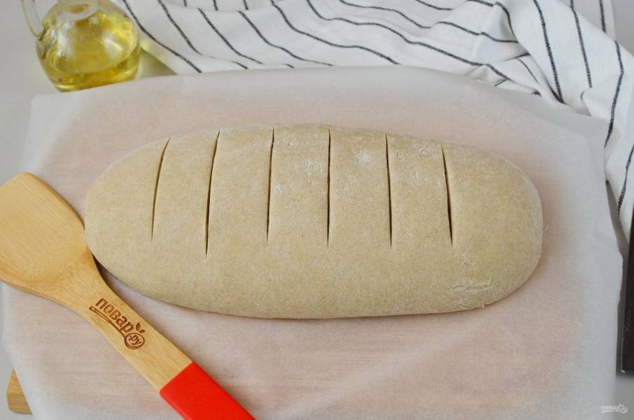 Сформируйте булку хлеба, выложите на пергамент, острым ножом сделайте надрезы. Накройте полотенцем и оставьте в тепле на 40 минут.
