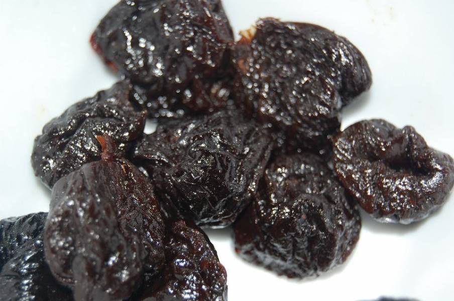 3. Пока части мяса жарятся, извлеките из чернослива косточки и нарежьте его мелко.