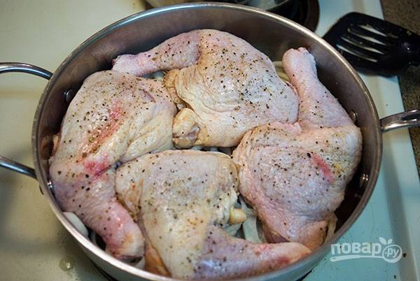 Включите духовку на 180 градусов, лук присыпьте солью, натрите солью и перцем окорочка и выложите их на лук. Положите лавровый лист.