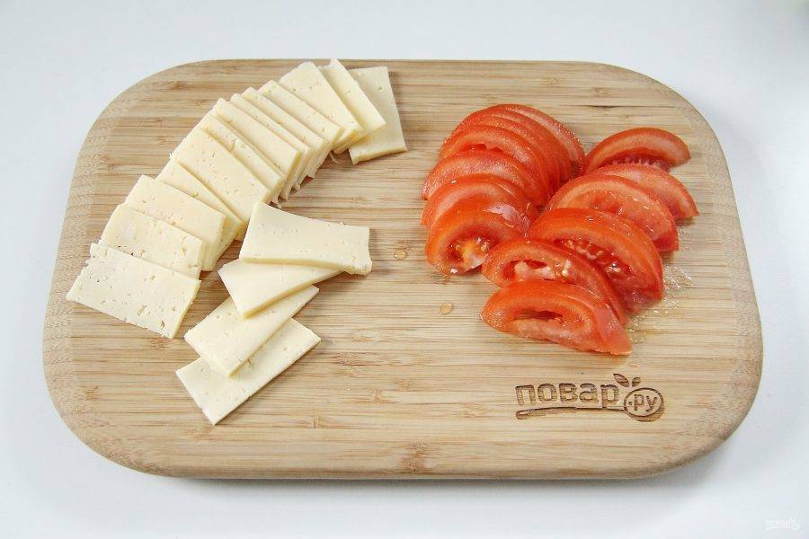 Нарежьте пластинами сыр. Помидоры помойте и нарежьте примерно таким же образом как и сыр.