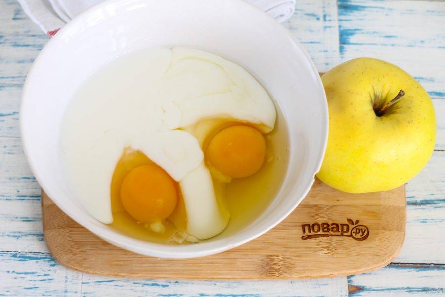 Вбейте в глубокую емкость куриные яйца, влейте кефир любой жирности, всыпьте сахарный песок и взбейте все венчиком примерно 2-3 минуты.