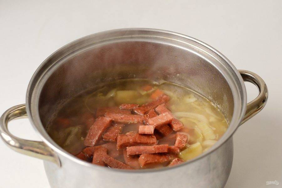 Добавьте жареную колбасу в суп, посолите и поперчите. В самом конце добавьте в суп мелко порубленную зелень. Доведите суп до кипения и снимите с плиты.

