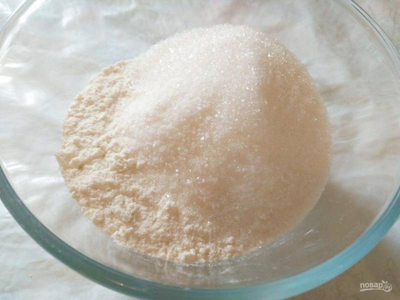 Пока тесто поднимается, приготовьте штрейзельную крошку. Для этого соедините в глубокой миске оставшуюся просеянную белую муку (100 г), сахарный песок (150 г) и ванильный сахар.