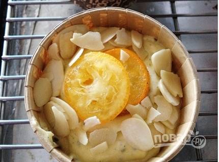 Уложите тесто в форму, посыпьте миндальными лепестками и сушеными апельсинами.