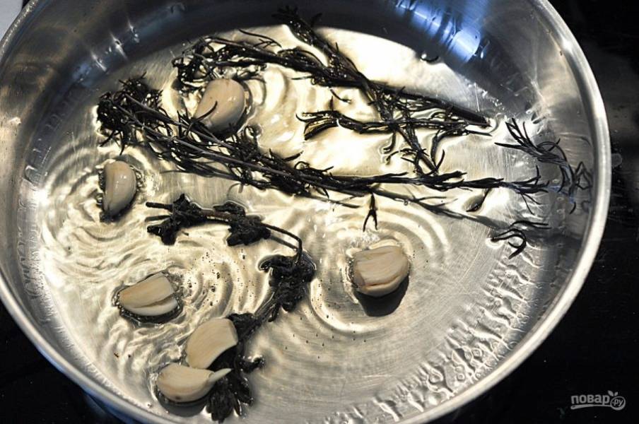 В разогретую сковороду влейте оливкового масла. Добавьте чеснок, розмарин и душицу.