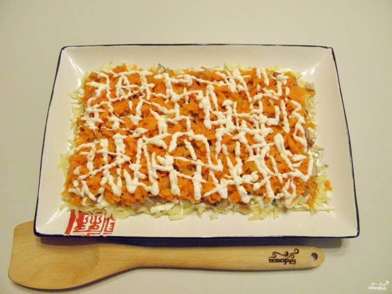 Накройте сельдь слоем тертой моркови и майонезом. Солите и перчите по вкусу.