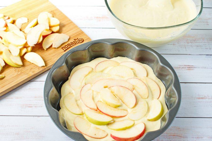 4.	Форму для запекания смажьте маслом. На дно формы выложите слой теста, и  ½ часть нарезанных яблок.
