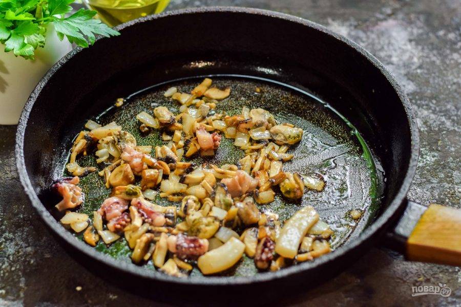 Разогрейте сковороду, добавьте ложку масла и поджарьте грибы с луком, после добавьте морепродукты и поджарьте еще несколько минут.