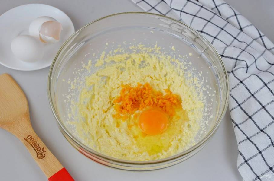 Добавьте в тесто апельсиновую цедру, одно яйцо. Взбейте миксером до гладкости, потом вбейте второе яйцо, снова взбейте.