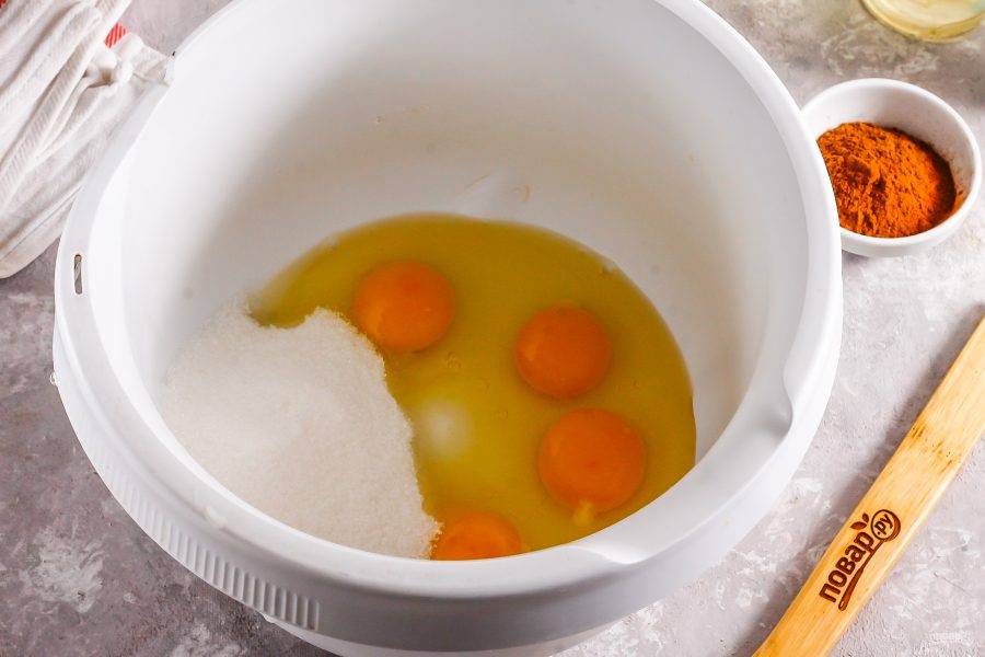 Куриные яйца вбейте в емкость кухонного комбайна. Всыпьте туда же соль и сахарный песок. Взбейте в течение 5 минут в пышную пену. Дольше взбивать не нужно, чтобы масса не расслоилась.