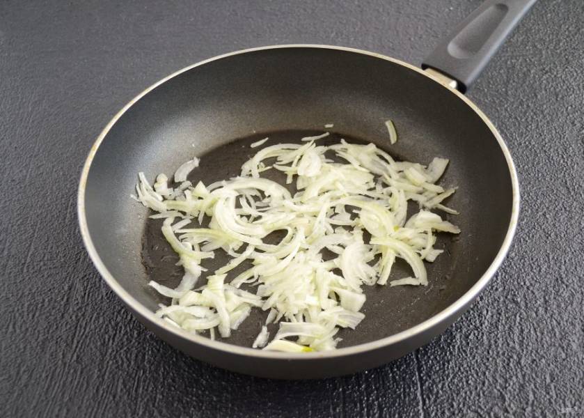 Нарежьте лук тонкими полукольцами и обжарьте на сковороде до мягкости.