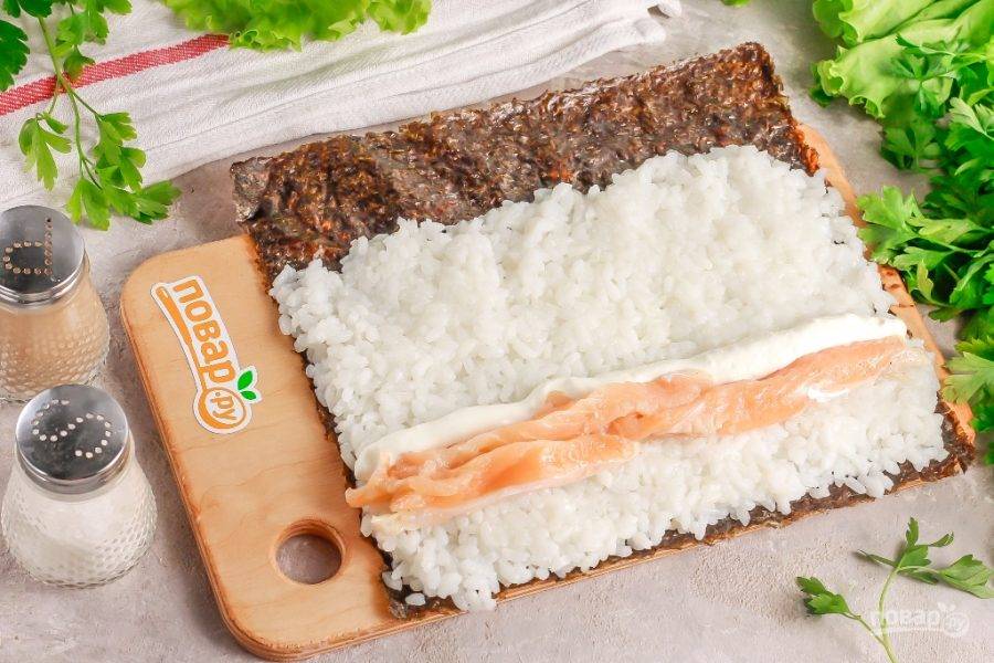 Выложите на край риса сливочный сыр и ломтики нарезки красной рыбы.