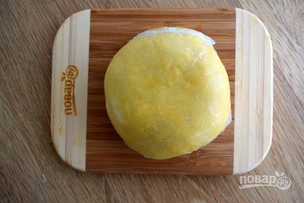 Холодное масло нарежьте на кусочки в чашу блендера, добавьте муку, желток и перемешайте до однородности. Добавьте натертый сыр, замесите руками тесто. Заверните его в пищевую пленку, положите в холодильник на 20-30 минут.