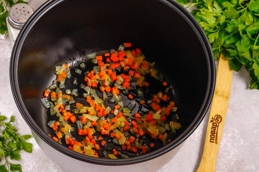 Морковь и лук очистите от кожуры вместе с картофелем, промойте в воде. Нарежьте лук и морковь мелкими кубиками. Активируйте на табло мультиварки режим "Жарка" и влейте в чашу растительное масло. Добавьте овощные нарезки и обжарьте примерно 8-10 минут до румяности.
