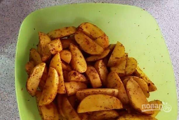 Положите картошку в миску, посыпьте специями и солью. Можно использовать уже готовые приправы для картофеля, которые продаются в магазине. Добавьте к клубням растительное масло и хорошенько все перемешайте. 