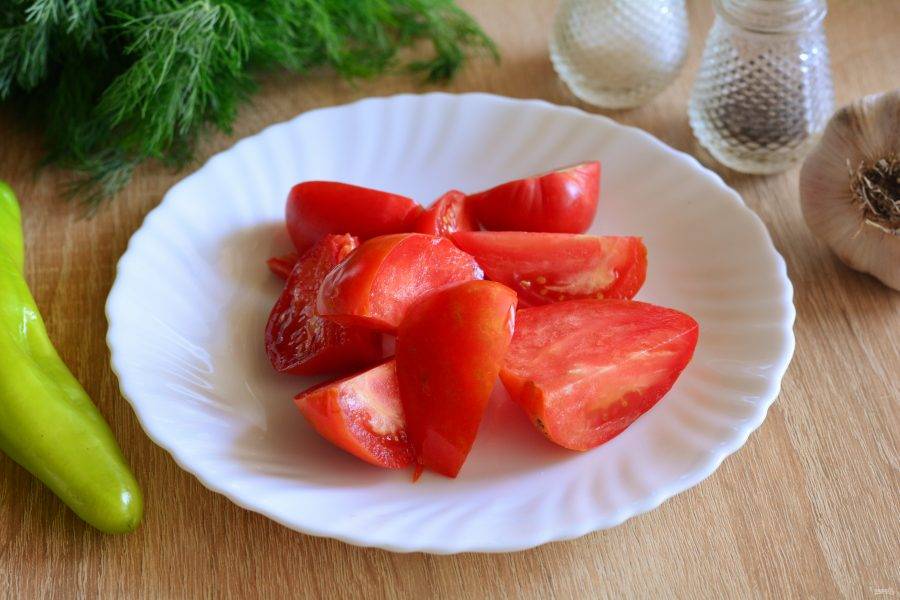 Промойте помидоры и нарежьте дольками, срезая плодоножки.