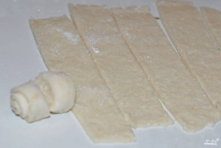Раскатайте тесто в пласт на присыпанной мукой поверхности. Посыпьте сахаром. Разрежьте на полоски толщиной в 5 см.