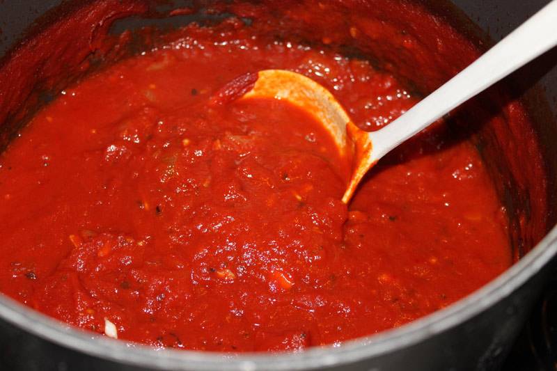 1. Для приготовления томатного соуса сперва нужно обжарить в небольшом количестве оливкового масла измельченный чеснок. Затем добавить соус (можно купить готовый или сделать самостоятельно, измельчив свежие помидоры без кожицы). Посолить и поперчить по вкусу, добавить специи. Соус нужно немного уварить на среднем огне, а затем отставить на время. 