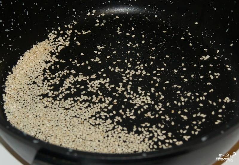 На сковороду, раскаленную на среднем огне, бросаем кунжут. Масло не наливаем, сковорода должна быть абсолютно сухой. Огонь делаем очень тихим, обжариваем кунжут минут 5, пока семечки не подрумянятся. Мешаем лопаткой, чтобы оттенок был равномерным.
