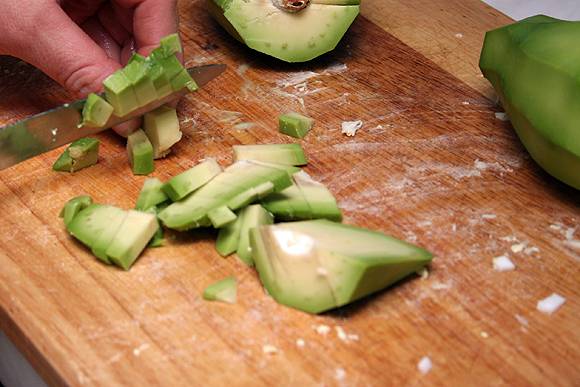 2. Из авокадо удаляем косточку и аккуратно вырезаем серединку. Мякоть тоже режем мелко. 