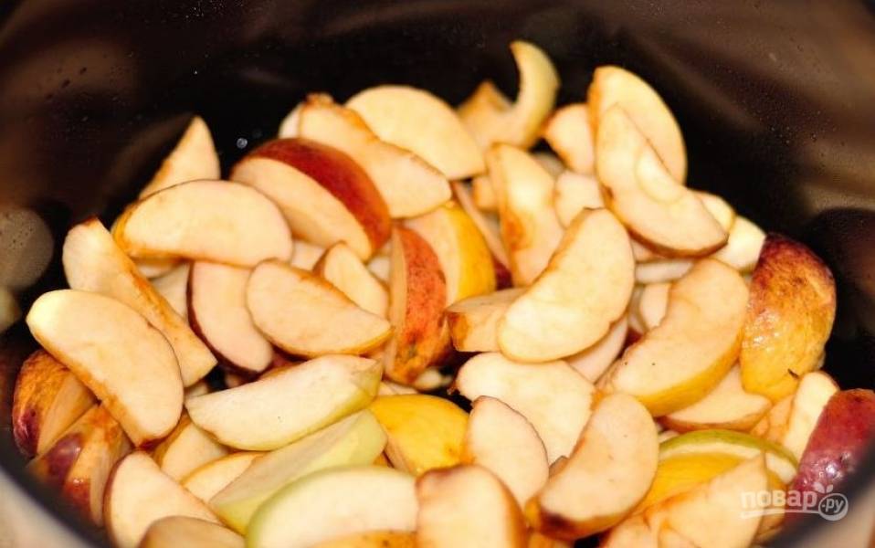 Чашу мультиварки смажьте маслом. Затем вымойте яблоки, обсушите их и нарежьте дольками. Удалите из яблок косточки. Выложите фрукты в чашу мультиварки. 