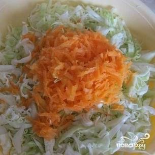 Морковь натрите на средней терке. Переложите капусту и морковь в глубокую миску. Мелко нашинкуйте лук.
