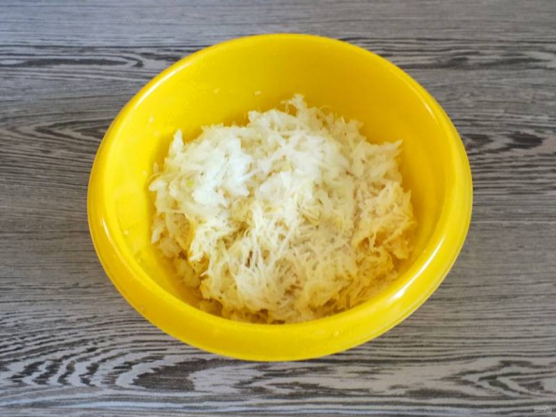 Очищенный картофель натрите на мелкой терке. Слегка отожмите от сока, но не сильно, иначе блюдо получится сухим. Переложите в чашу. Также натрите на мелкой терке вторую половину луковицы и смешайте с картофелем.
