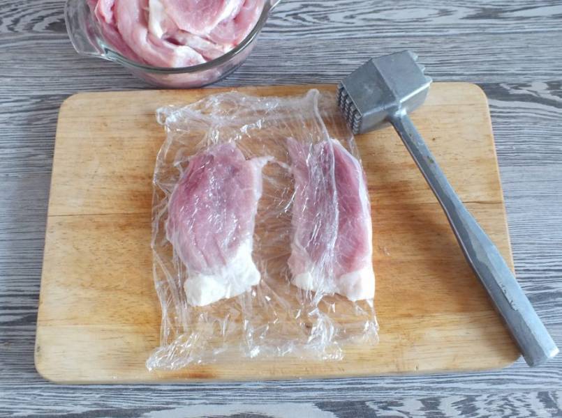Оберните кусочки мяса пищевой пленкой и хорошо отбейте.