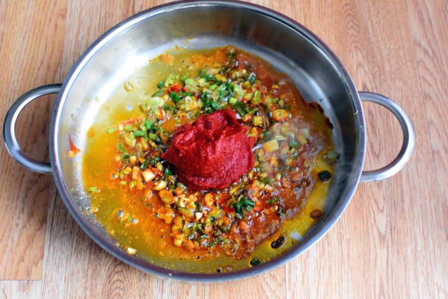 Добавьте томатную пасту и паприку. Помешивая, прогрейте до окрашивания масла в красный цвет.