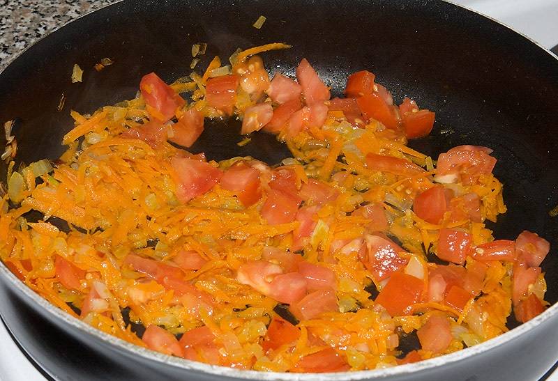 4. Очистить и натереть на терке морковь, добавить на сковороду. Туда же отправить томатную пасту или нарезанный помидор. Продолжать жарить. 
