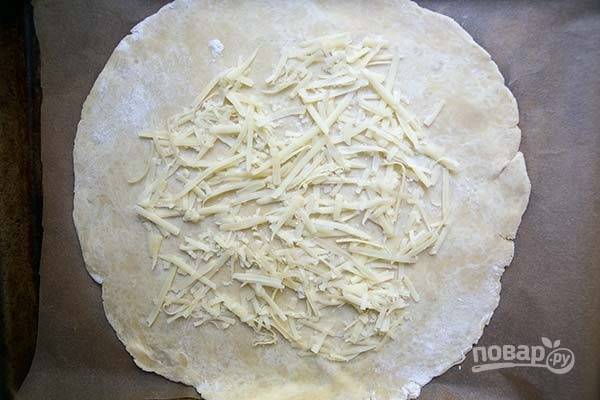 3.	Раскатайте тесто в тонкий пласт, выложите по центру половину натертого сыра.