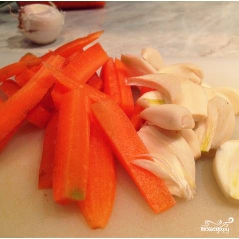 Очищенную морковь нарежьте небольшими брусочками (длина брусочка примерно 3-4 см). Очищенные зубчики чеснока разрежьте пополам.