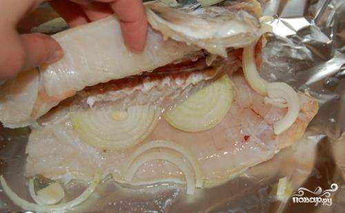 1. Очистить треску и натереть солью. Выложить внутрь рыбы половину нарезанного полукольцами лука. 