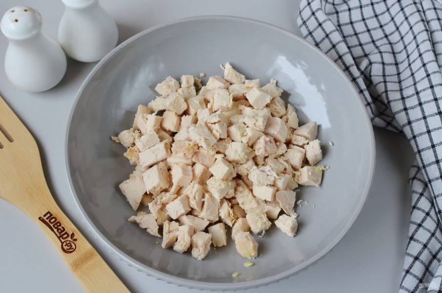 Порежьте куриное филе крупными кубиками. Выложите в большой салатник.