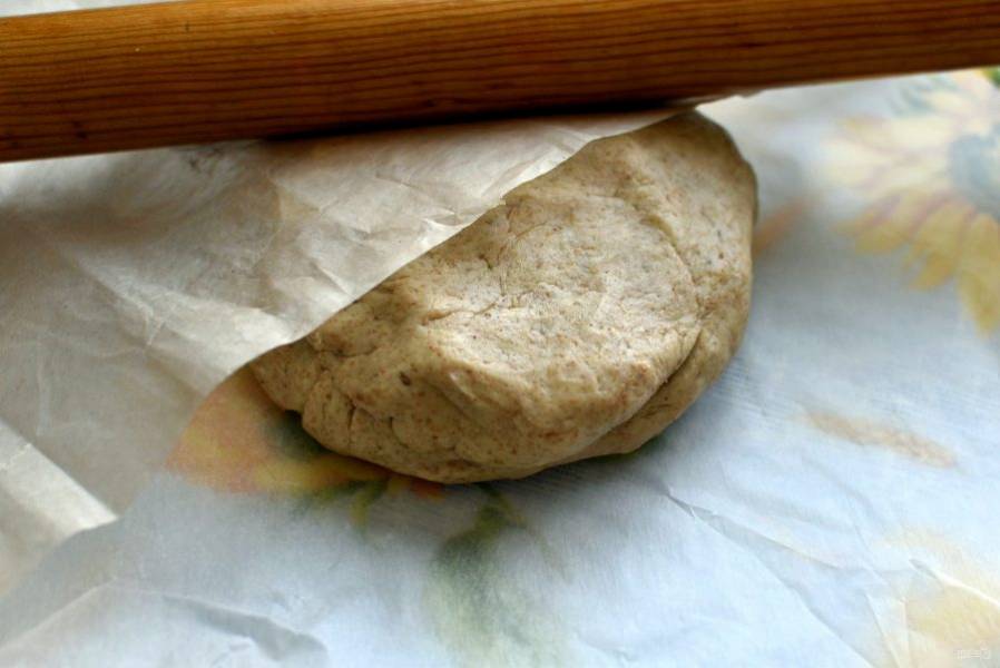 Раскатайте тесто между двумя листами пекарской бумаги в тонкий круг толщиной не более 1 см.  