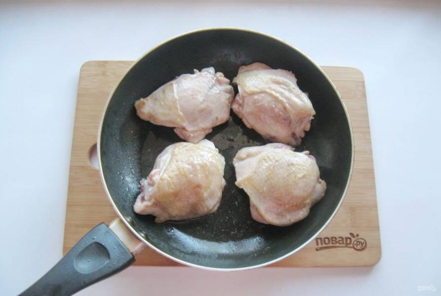 Налейте подсолнечное масло и слегка обжарьте куриные бедра в сковороде.