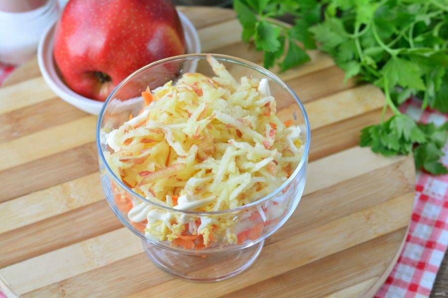 Натрите сочное яблоко на терке и выложите следующим слоем в салат.
