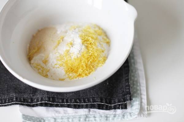 Для теста просейте муку, соедините ее с солью, сахаром и разрыхлителем. Вымойте и обсушите лимон, снимите с него цедру и добавьте ее к мучной смеси. 