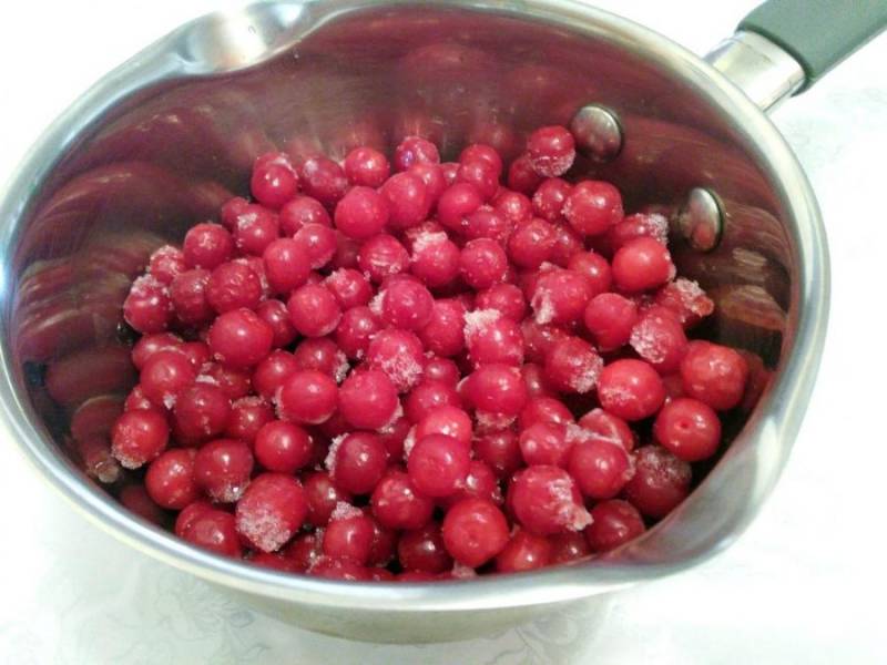 Выложите ягоды в ковш и влейте воду. Поместите ковш с ягодами на медленный огонь и периодически помешивайте содержимое ложкой. Варить ягоды не нужно, необходимо, чтобы они прогрелись и обмякли. 