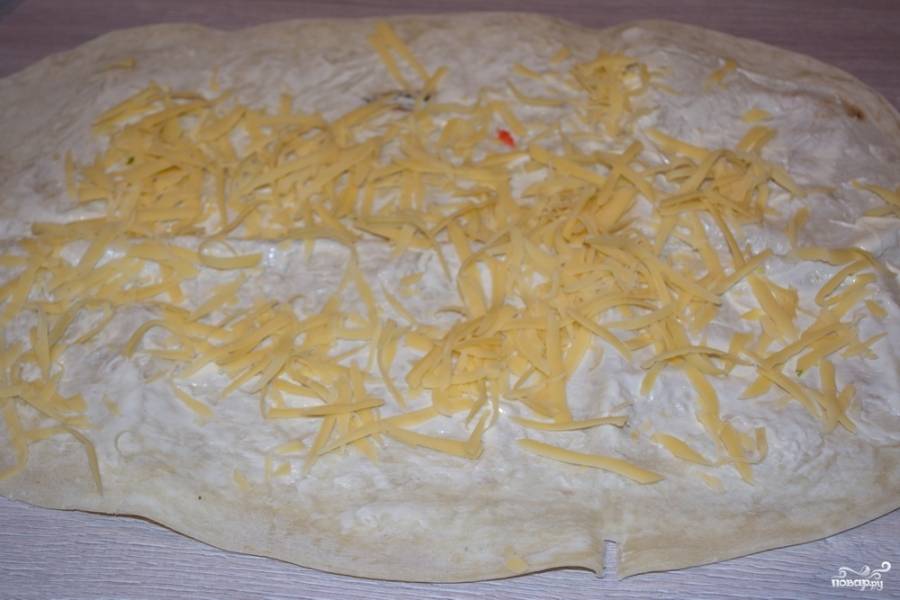 На крупной терке натрите твердый сыр. Распределите сыр по всему лавашу.