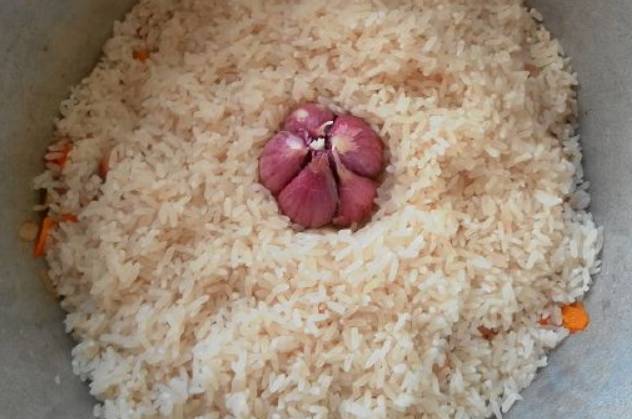 Засыпьте промытый рис. В середину риса втыкаем головку чеснока.
