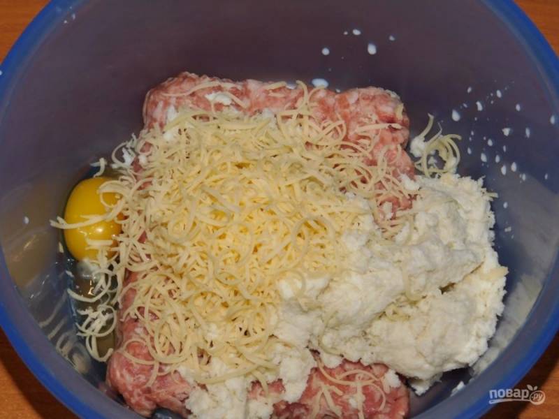 Соедините фарш, размоченный и отжатый батон, яйцо и половину тертого сыра. Хорошо перемешайте.
