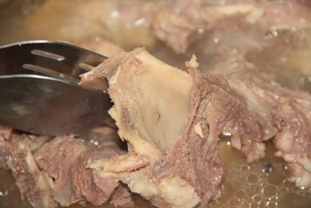 Готовность проверяем ложкой. Мясо можно считать готовым, если оно начинает отслаиваться от костей. 