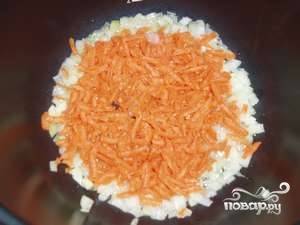 Пока лук обжаривается, натрите очищенную морковь на крупной терке. Добавьте морковь к луку.