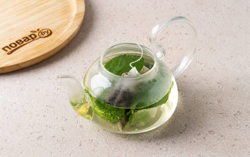 Переложите в заварочный чайник мяту и зелёный чай. Залейте кипятком и оставьте завариться на 5-10 минут.