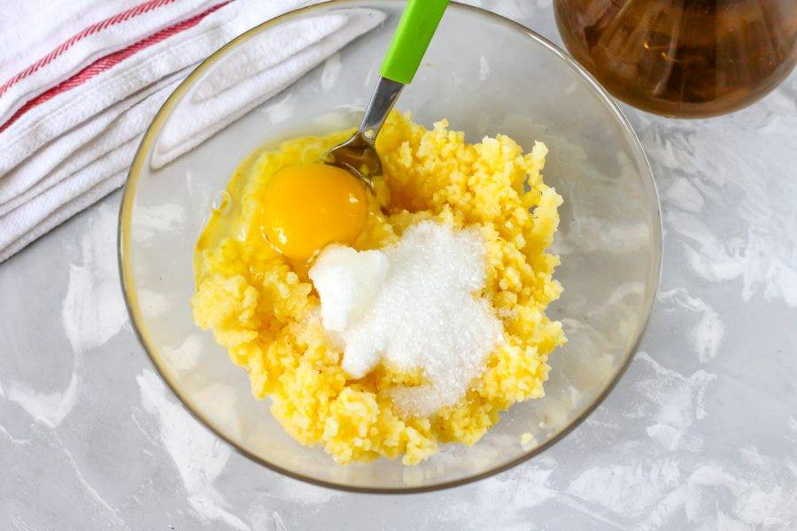 Спустя указанное время, выложите кашу в салатник или глубокую миску, дайте ей остыть около 15 минут. Затем вбейте в емкость куриное яйцо, всыпьте сахар.