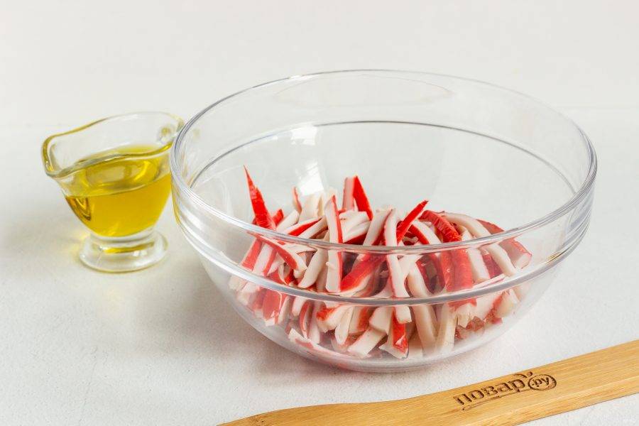 Крабовые палочки нарежьте тонкой соломкой, выложите в салатник.