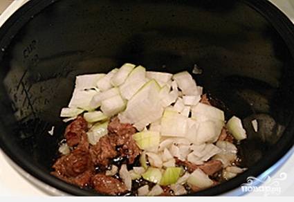 Помойте и нарежьте порционно мясо. Лук почистите и порежьте кубиками. Соедините эти два ингредиента в чаше мультиварки. Готовьте в режиме "Жарка" 15 минут с маслом.