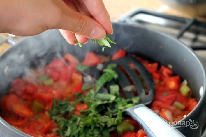 Посолите и поперчите соус по вкусу. Добавьте томатную пасту, орегано и порезанный базилик. Тушите около часа, помешивая каждые 10 минут. За 15 минут забросьте в соус нарезанные цукини и потушите.