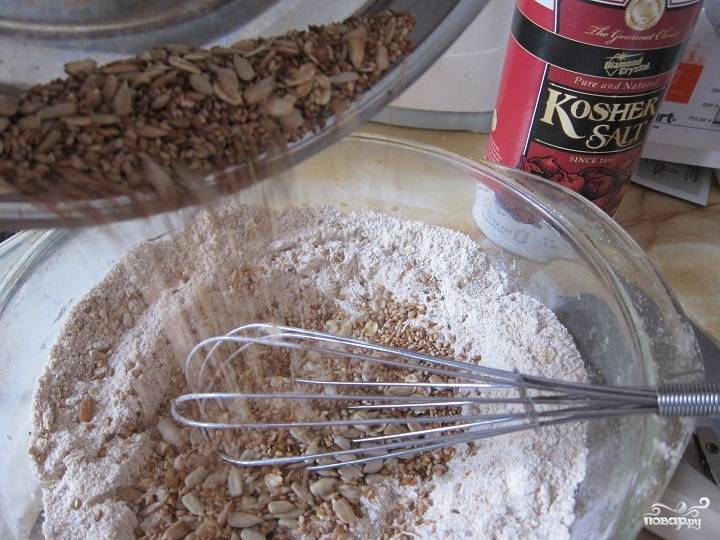 1. Смешаем отдельно просеянную муку с солью, отдельно на сухой сковороде обжарим лен, кунжут и семечки. Всыпаем семена в сухую смесь, перемешаем. Немного семечек оставьте для украшения. 